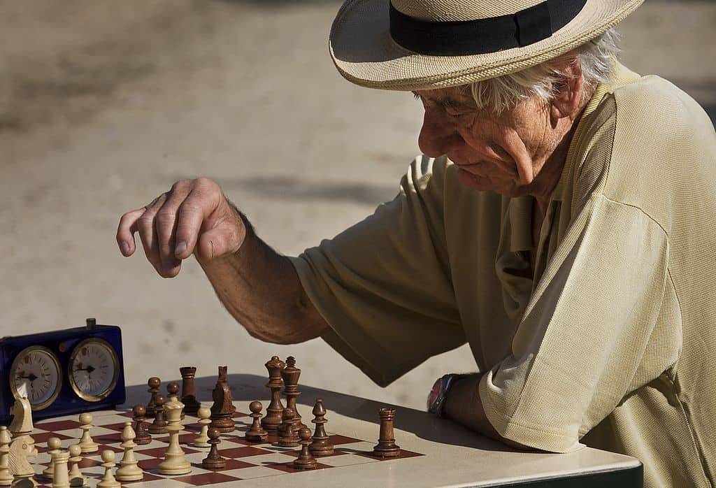 old man playing chess in a park