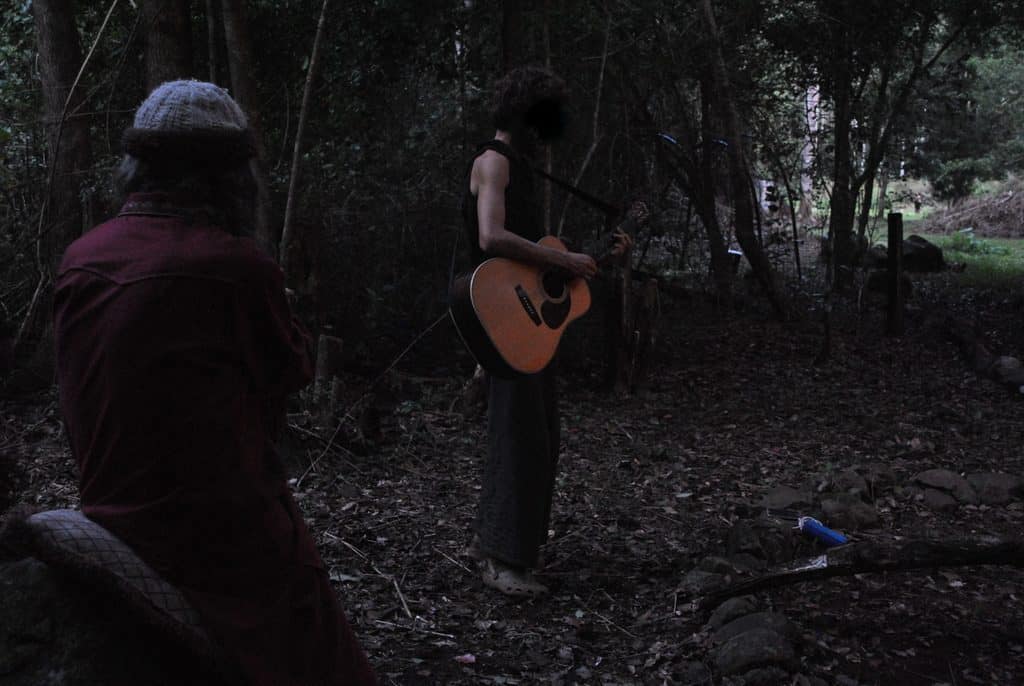 man playing guitar in woods