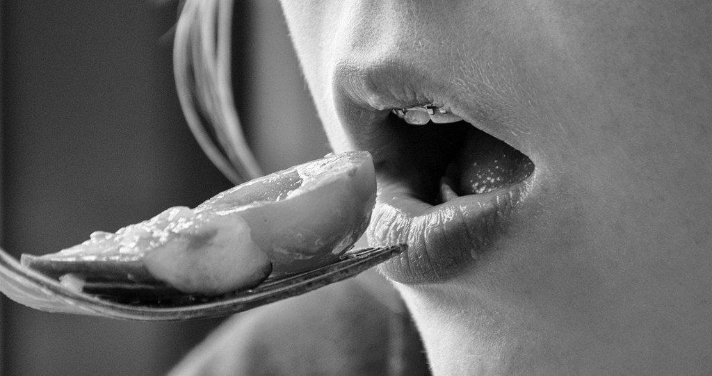 black and white photo of woman eating a bite of food