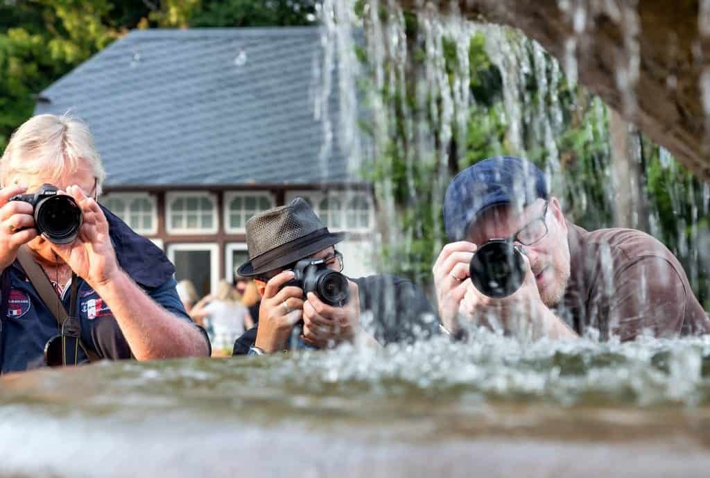 three men with cameras focussing on stream