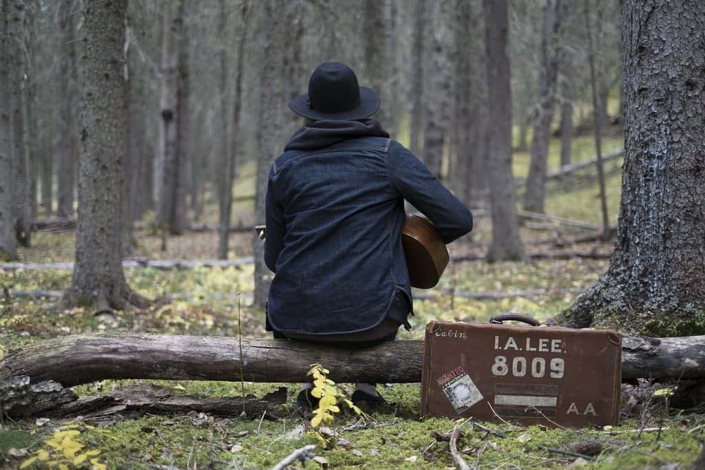 guy sitting on a log playing guitar