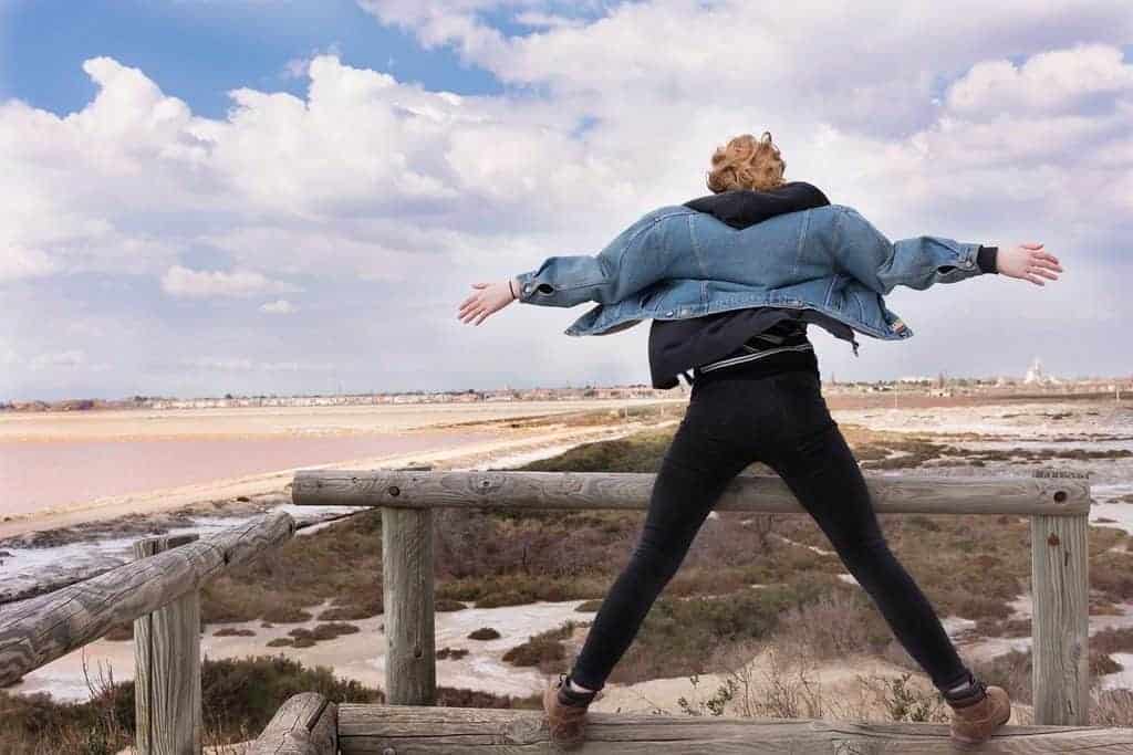 woman standing on bridge with arms wide
