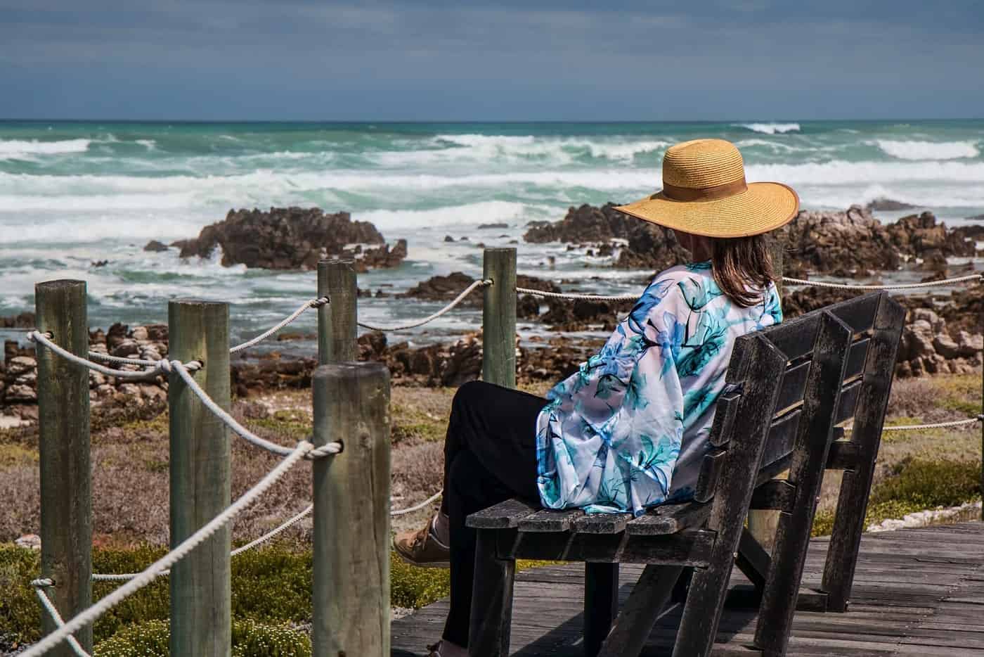 woman resting on bench next to sea