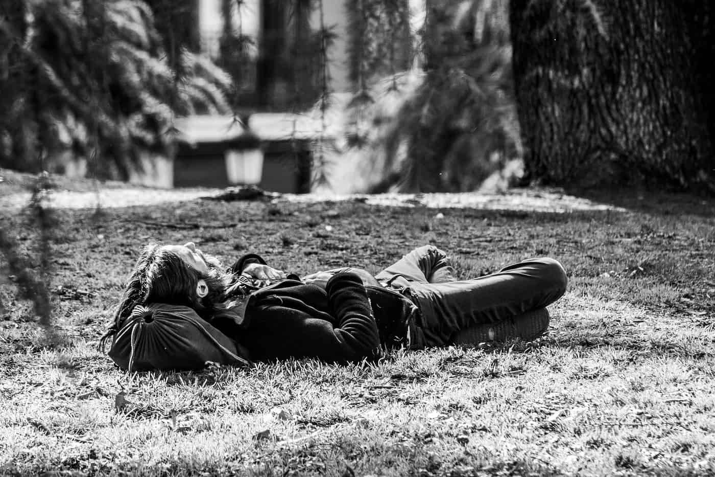 Man lying on grass with head on bag - Poems by Mike Larcombe