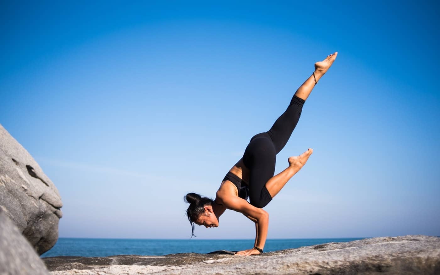 Woman doing Yoga pose on rock - A guide to Koh Phangan, Thailand