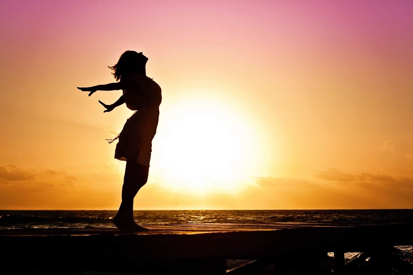 Woman standing on dock at sunrise - A guide to Koh Phangan, Thailand