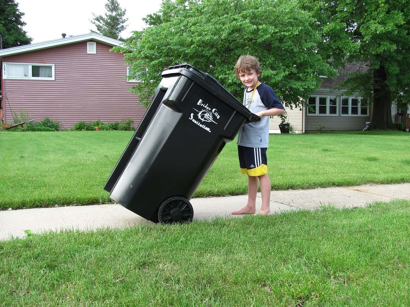 Young boy pushing trash can