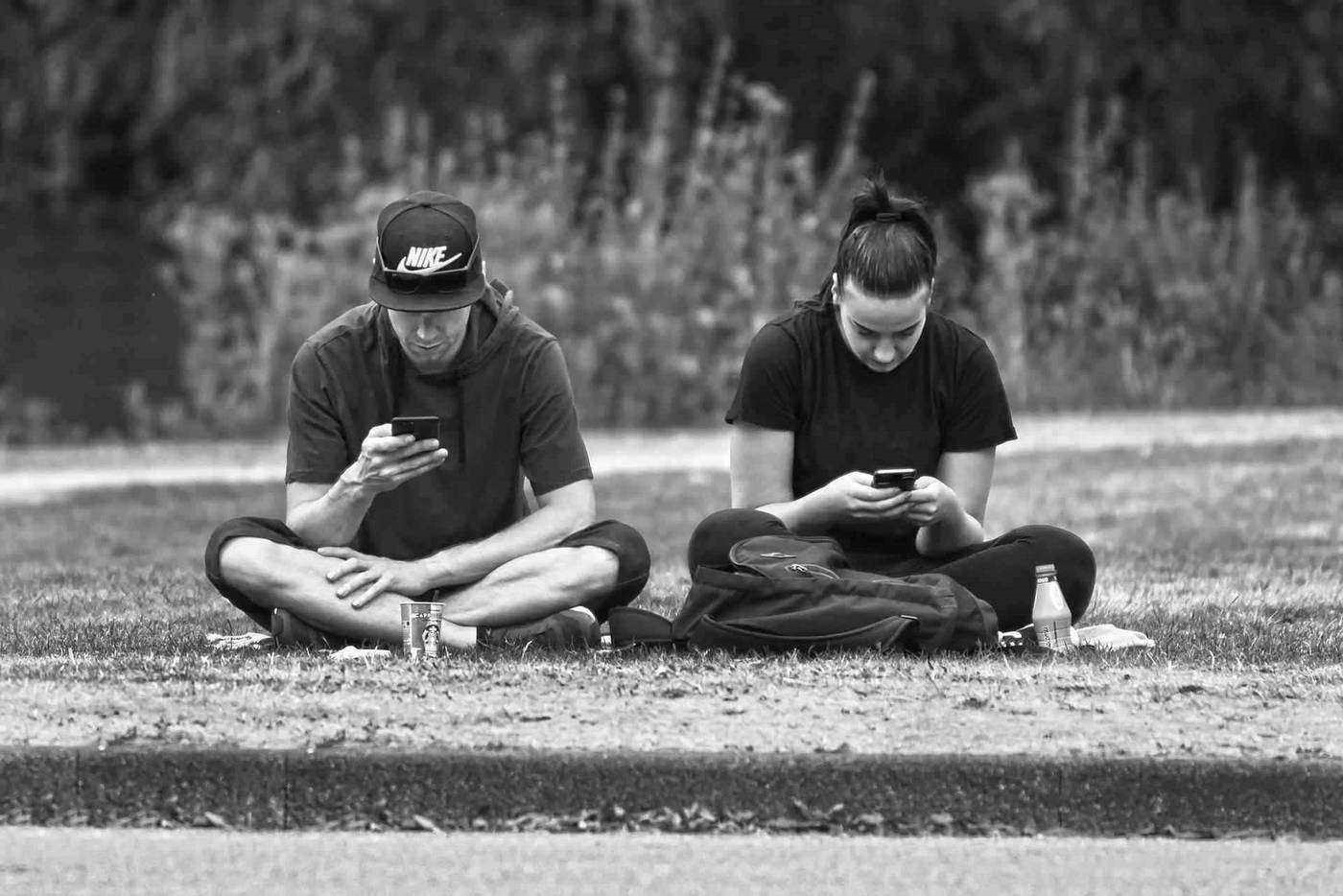 Two young people on cell phones side by side