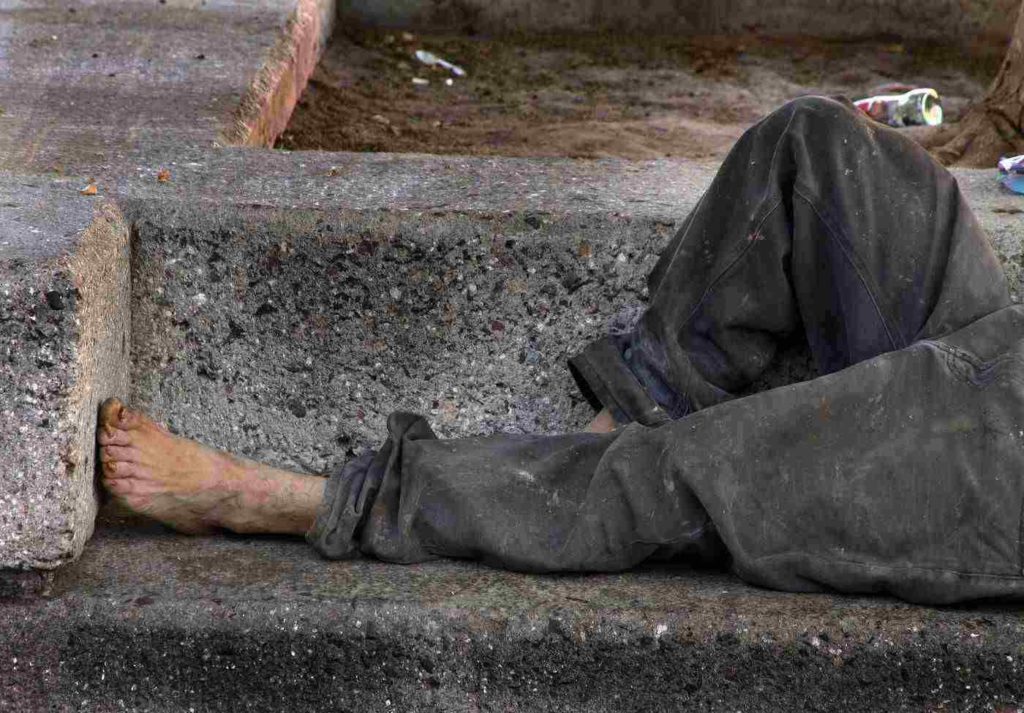 Homeless man on bench, barefoot
