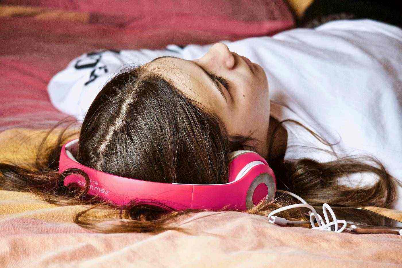Young woman lying on bed with headphones